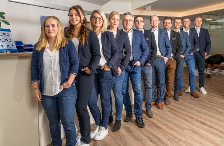 Das Team der UNIQA Generalagentur Flachgau in einer Reihe aufgestellt, in dunkelblauer Kleidung